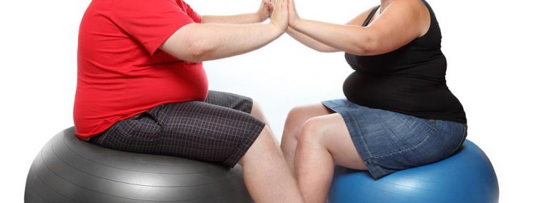 A man and woman sitting on exercise balls.